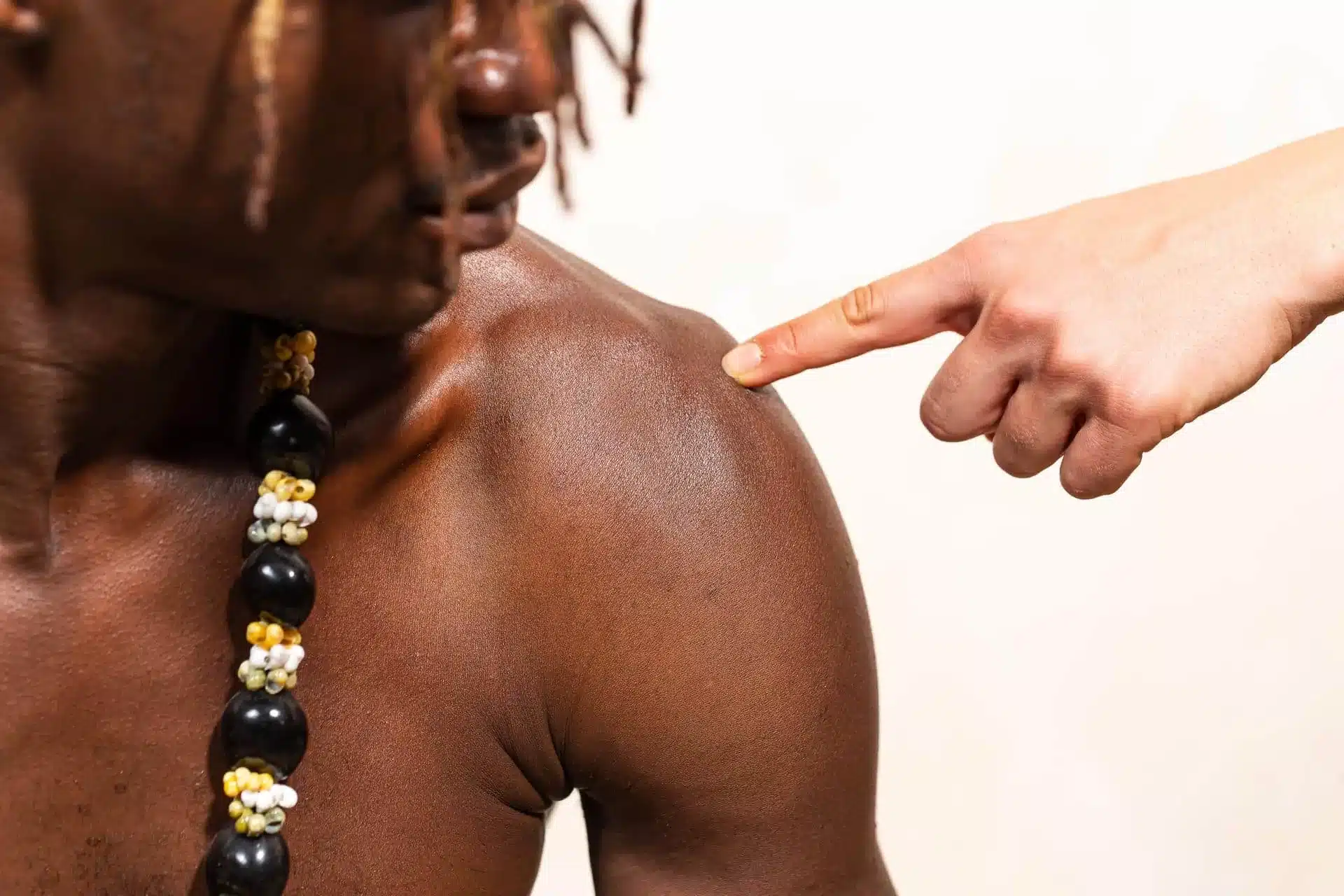 Finger pointing to the acromioclavicular (AC) joint on a patient's shoulder to demonstrate the location of AC joint pain and shoulder injuries treated at Cavanaugh Chiropractic in Lafayette, LA.