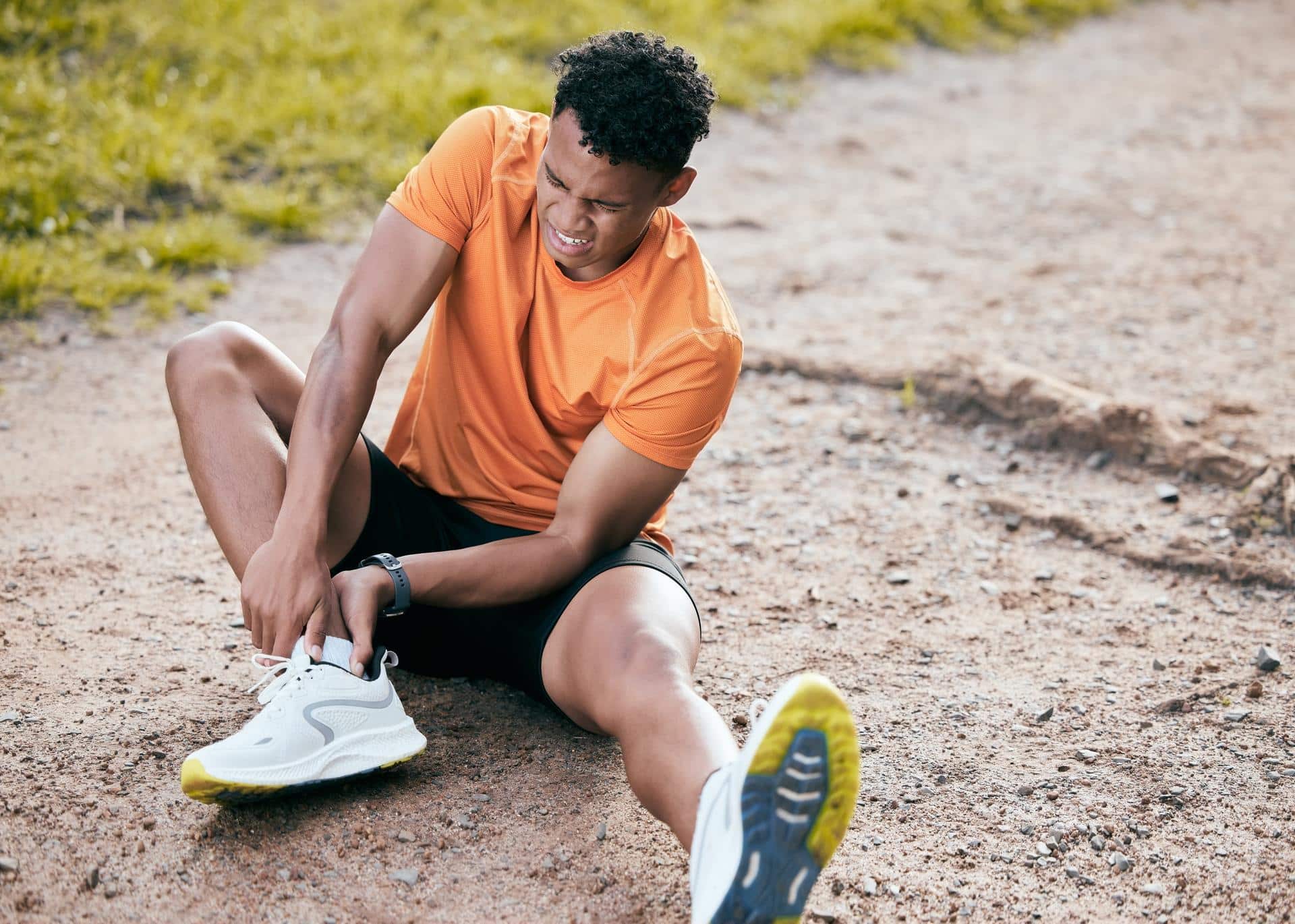 Runner holding his ankle in pain from Achilles tendinitis, a common overuse injury seen in Lafayette, LA.