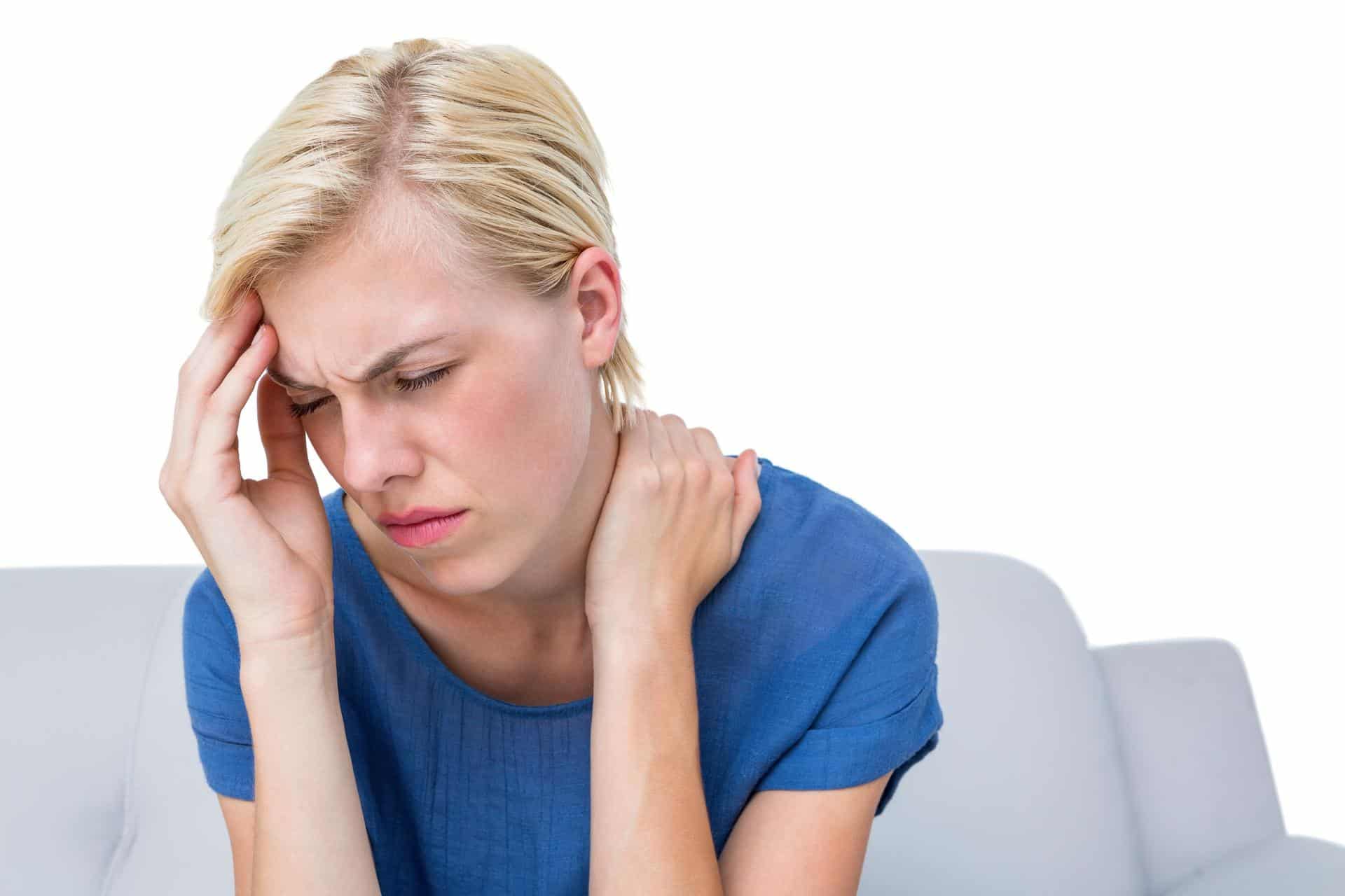 Woman with a headache and neck pain, possibly experiencing autonomic dysfunction, sitting on a couch in Lafayette, Louisiana