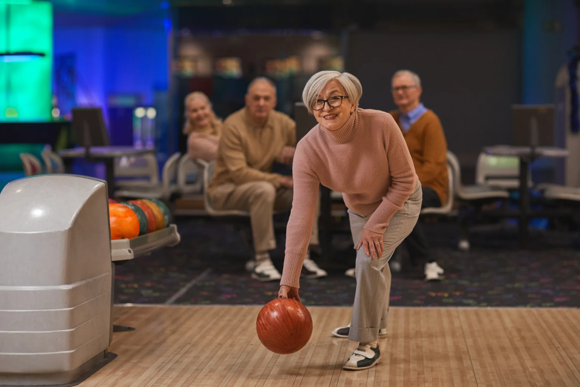 Smiling older woman bowling with friends, representing chiropractic care for everyday aches and injuries in Lafayette, Louisiana